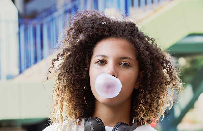 1980s vibe girl blowing bubblegum wearing large Sterling Silver hoop earrings